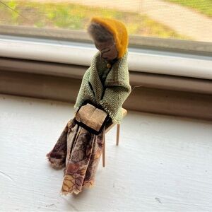 Antique miniture doll sitting in wooden chair.